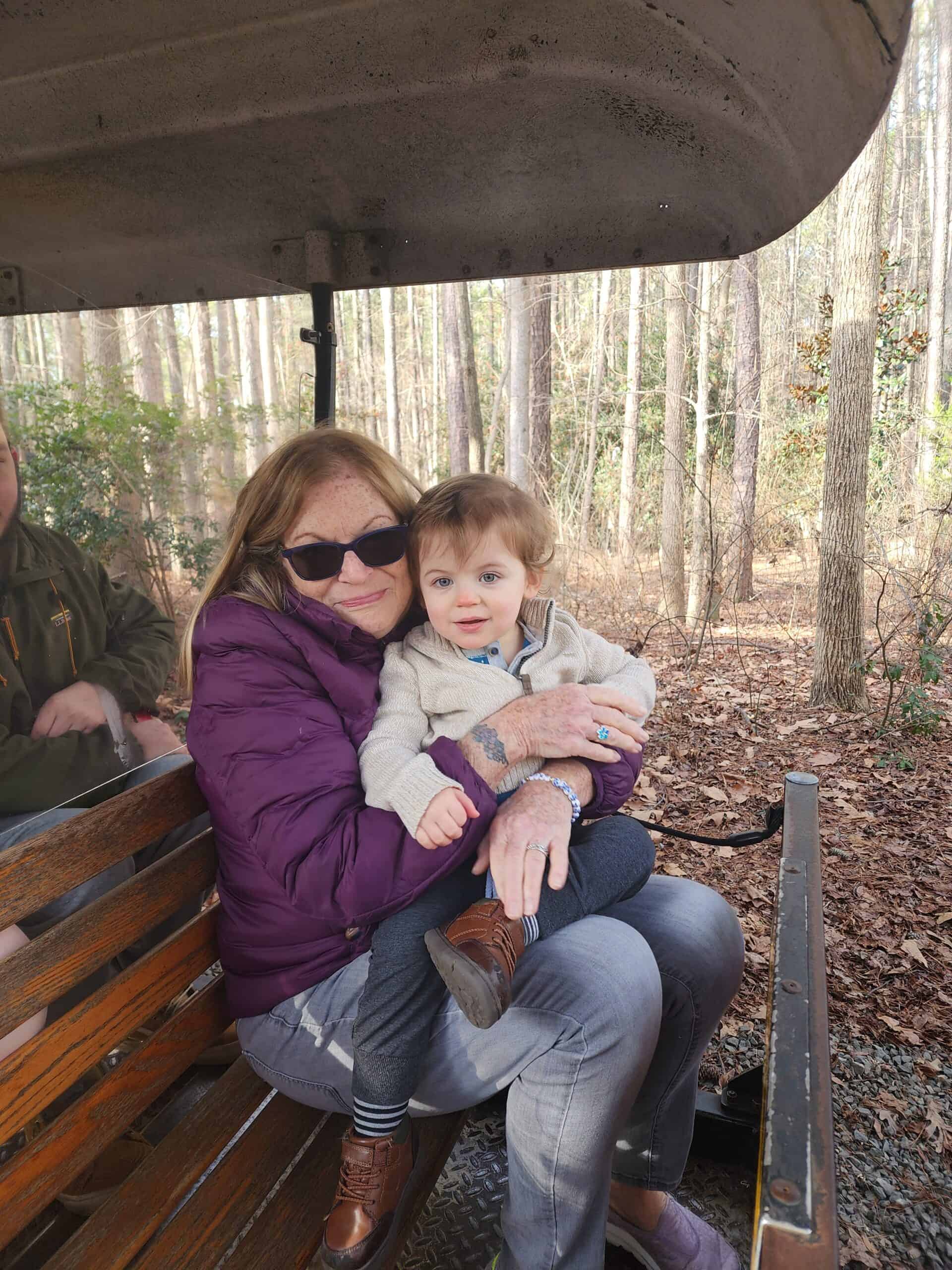 A heartwarming moment as a grandmother and toddler enjoy a train ride surrounded by the serene woods at the Museum of Life and Science in Durham, capturing a family experience at the educational attraction