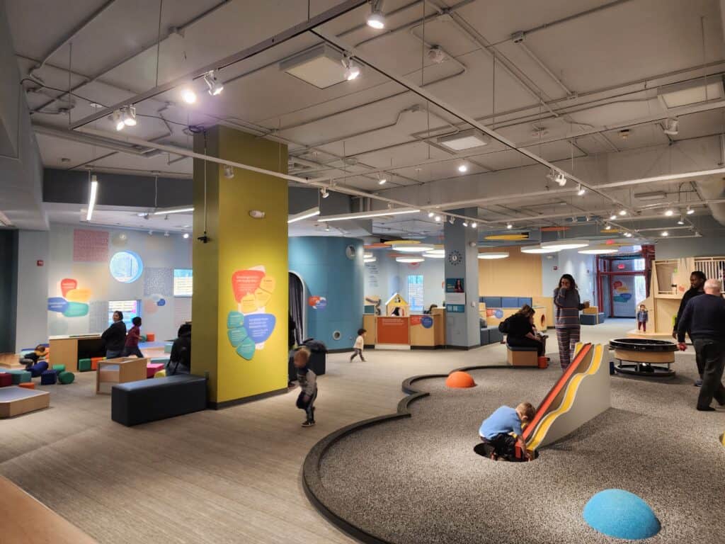 Children engage in playful learning at a kids' museum in Durham, with interactive exhibits, foam building blocks, and colorful, informative displays, providing a dynamic environment for educational play and discovery.